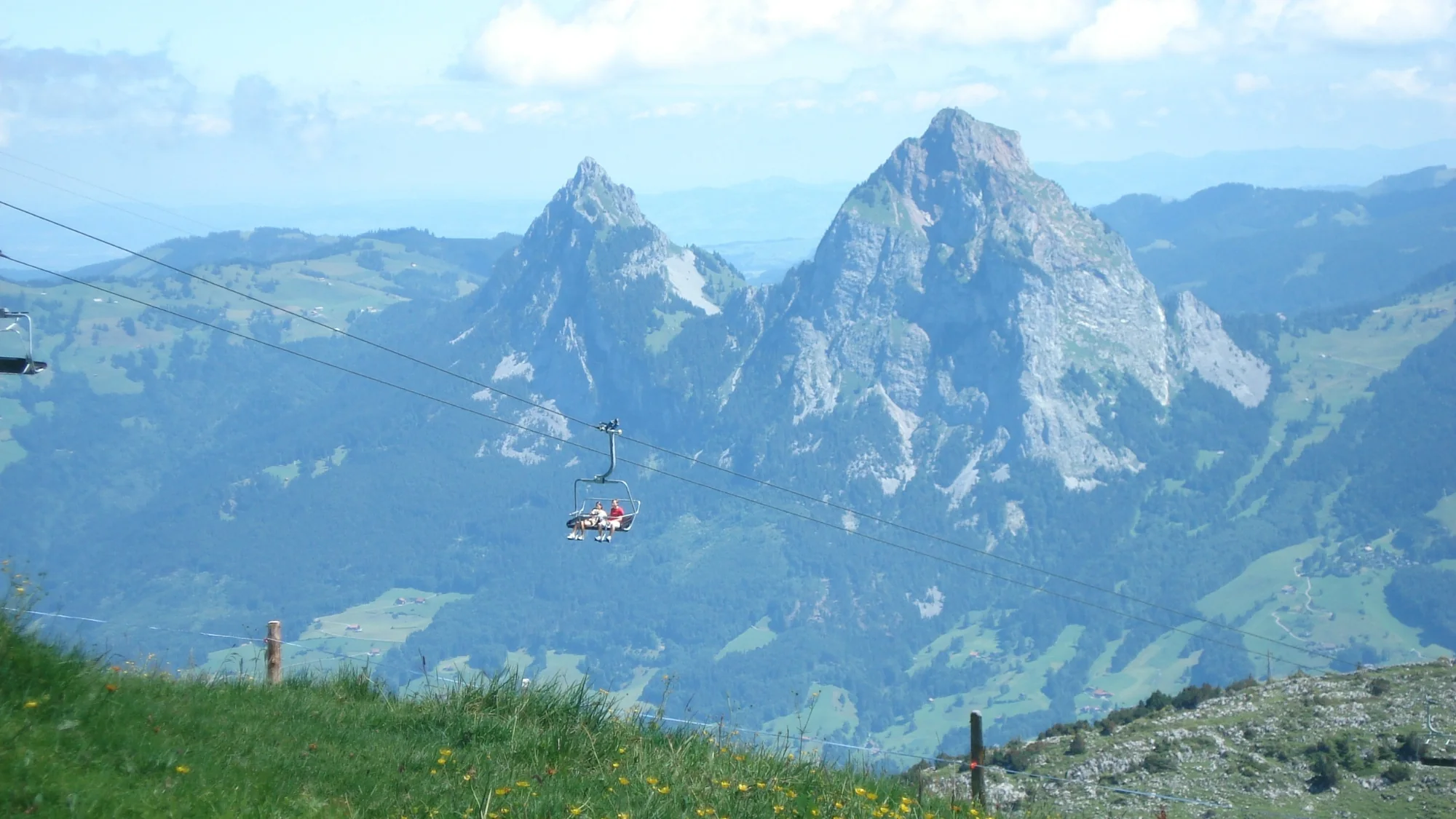 Grosser und Kleiner Mythen über den Alpweiden, davor ein Sessel der Bergbahn