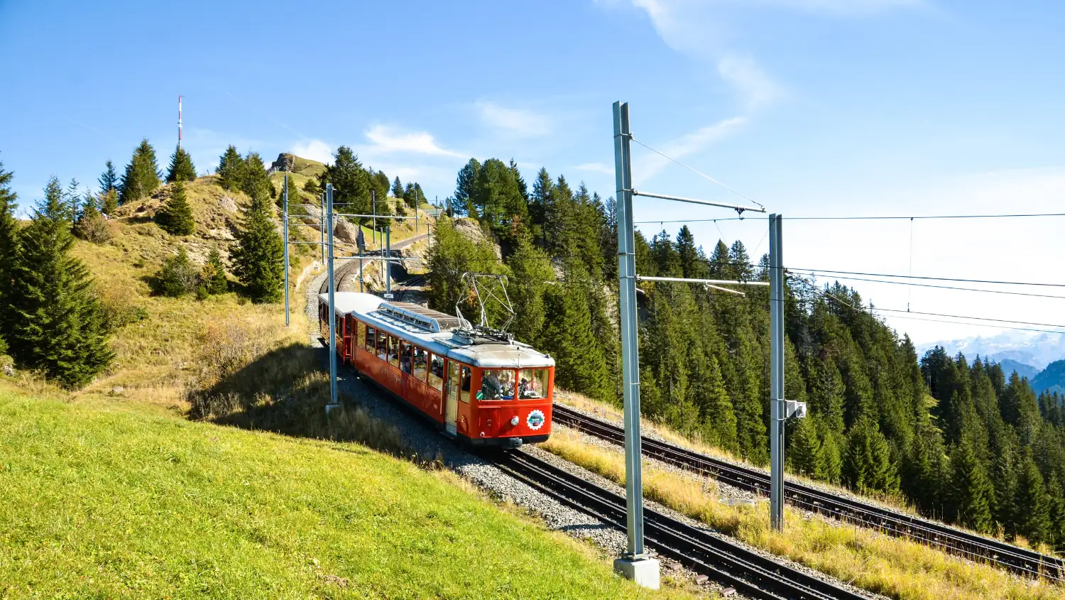 Train rouge du Rigi montant vers le sommet à travers les prairies d'altitude